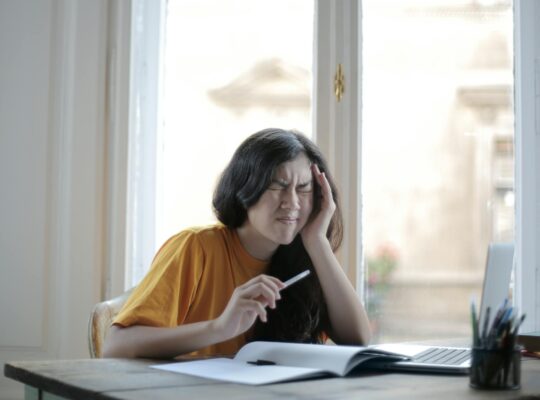 female student suffering from headache at home